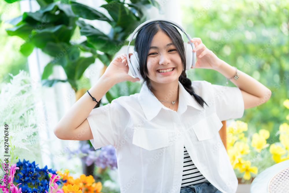 Happy of cute smiles Asian of attractive young Cute little girl wearing white wireless headphones and listening music enjoying favourite audio at the cafe on vacation at a coffee shop. Happy of cute smiles Asian of attractive young Cute little girl wearing white wireless headphones and listening music enjoying favourite audio at the cafe on vacation at a coffee shop.