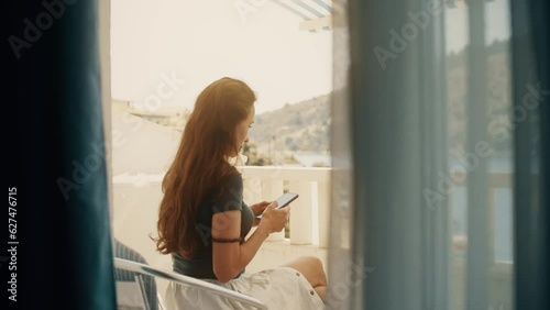 A beautiful woman uses her smartphone on a seaview terrace photo