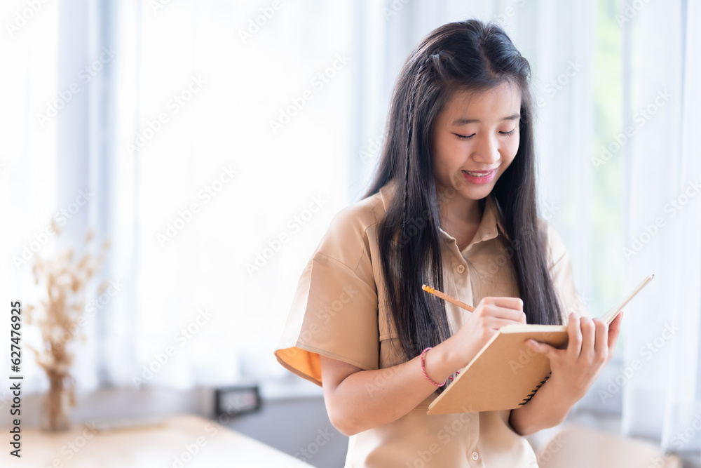 Happy of Young asian teen girl college student Taking written Notes to on notebook.Online education, elearning concept,freelance people businessfemale Happy of Young asian teen girl college student Taking written Notes to on notebook.Online education, elearning concept,freelance people businessfemale