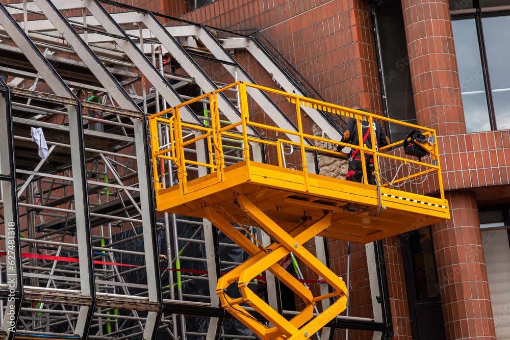 Yellow hydraulic lifting platform with bucket cabin on a telescopic lift. Yellow hydraulic lifting platform with bucket cabin on a telescopic lift.