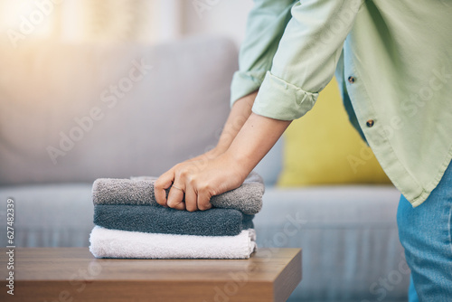 Hands, home and laundry on living room table for hygiene, cleaning and folding for housework in morning. Woman, fabric and cotton towel on desk for organized house, service and routine in apartment