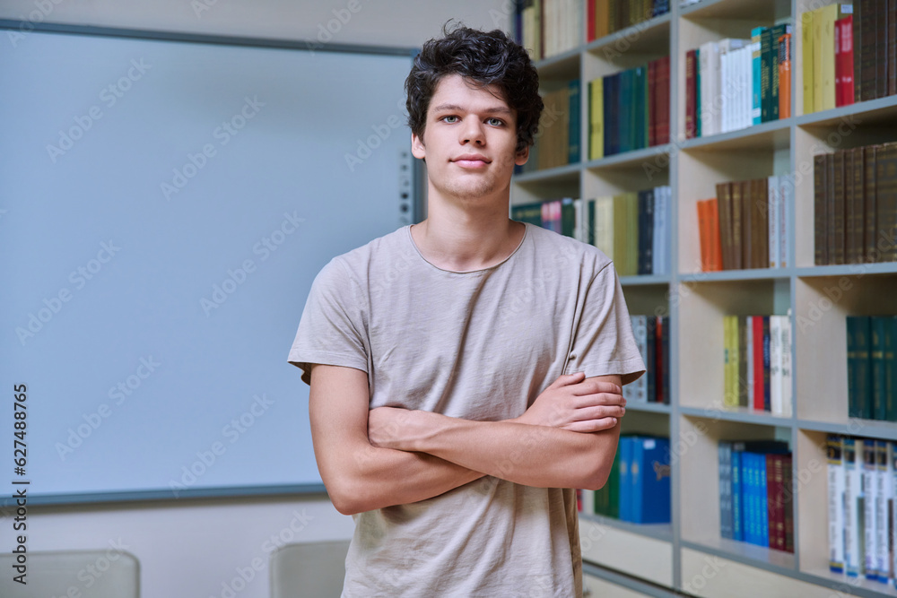 Fototapeta premium Portrait of confident guy college student looking at camera inside library