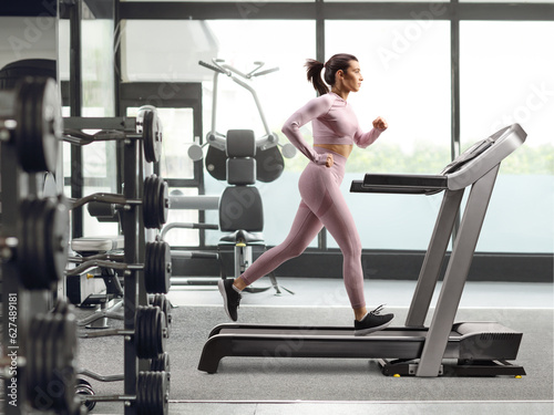 Full profile shot of a female running on a treadmill at a gym