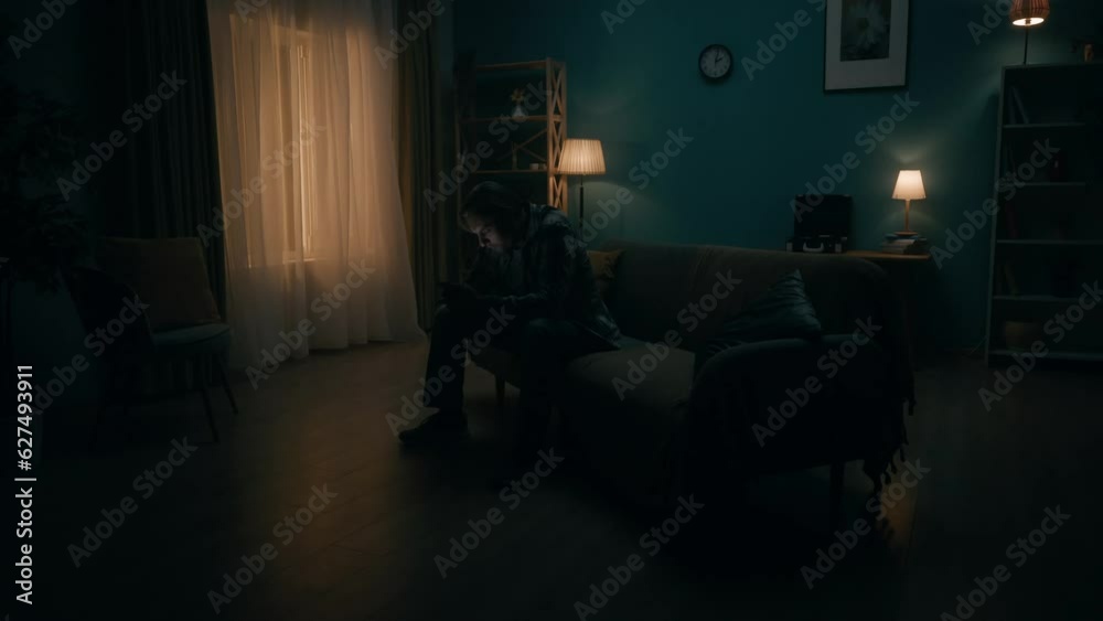 Smartphone addiction and depression. A young man sits in a dark room on a sofa with a phone in his hands, plays an online game, a casino. The man loses and shakes his head. Change of day and night.