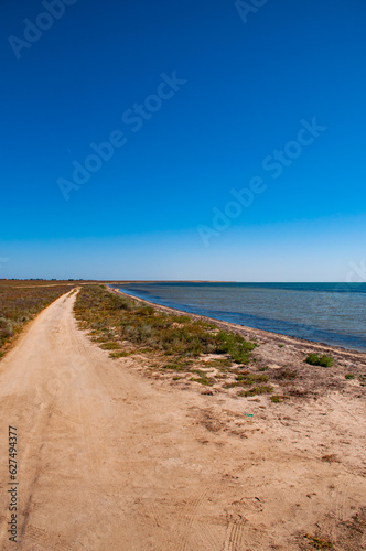 Dirt road along the salt lake against a clear blue sky