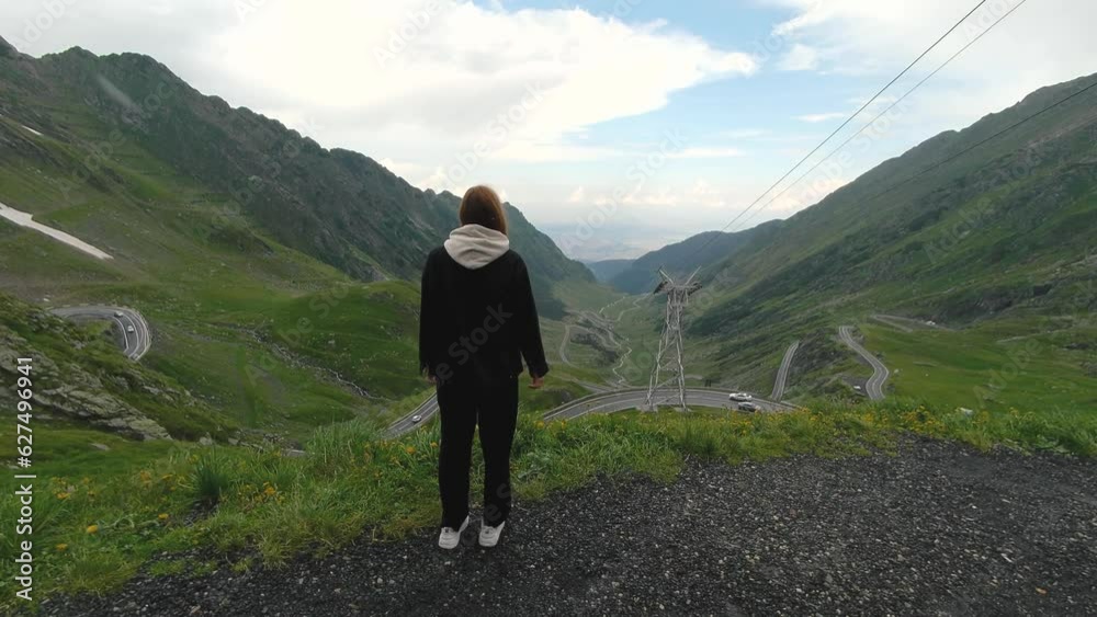 A beautiful Ukrainian young woman traveler walks along the most beautiful high mountain road in Romania Transfagaras highway. Transfagarasan, Carpathian mountains in Romania A beautiful Ukrainian young woman traveler walks along the most beautiful high mountain road in Romania Transfagaras highway. Transfagarasan, Carpathian mountains in Romania
