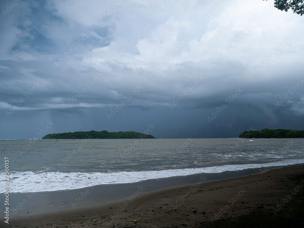 Moody weather with dark storm clouds over tropical beach during rainy season Moody weather with dark storm clouds over tropical beach during rainy season