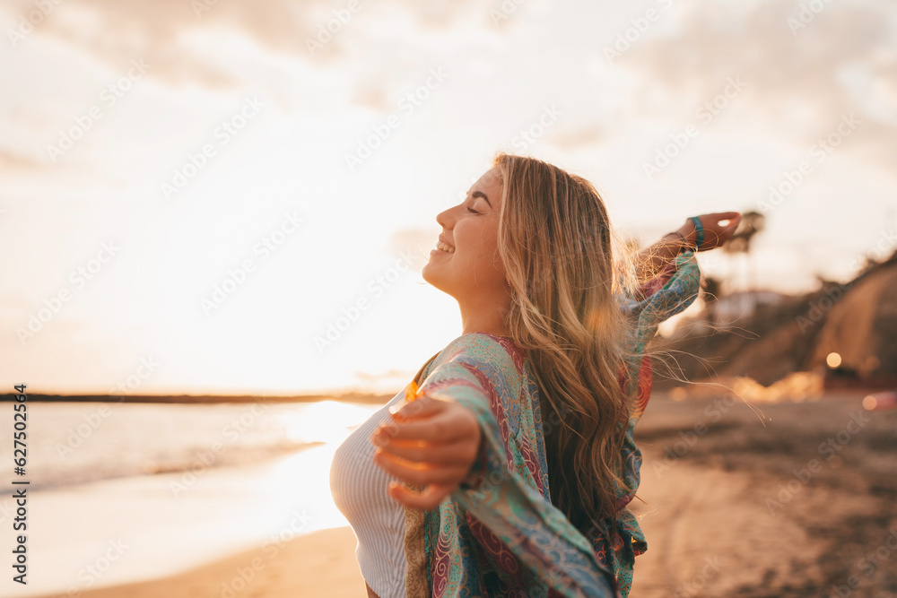 Portrait of one young woman at the beach with openened arms enjoying free time and freedom outdoors. Having fun relaxing and living happy moments.. - obrazy, fototapety, plakaty 