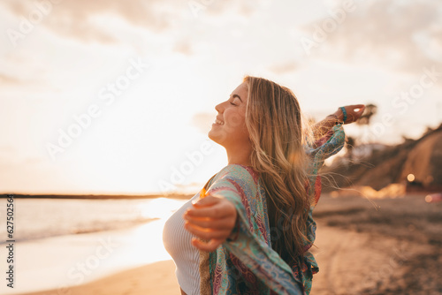 Portrait of one young woman at the beach with openened arms enjoying free time and freedom outdoors. Having fun relaxing and living happy moments.. photo