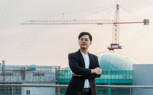 An Asian Businessman contemplating the future atop a High-rise Building.