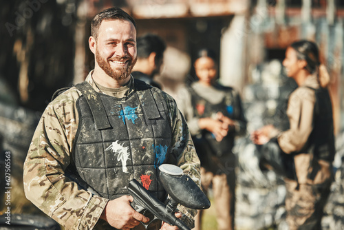 Paintball game, portrait and happy man in battlefield, challenge or military mission, gun fight or conflict. Happiness, soldier smile and male player ready for war training, action or battle training © Daniels C/peopleimages.com