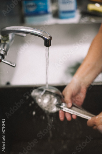 hand washing a large spoon in an industrial kitchen volunteer worker employee