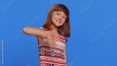 Young cute brunette school girl smiling friendly at camera and waving hands gesturing hello or goodbye, welcoming with hospitable expression. Preteen female child kid isolated on blue background