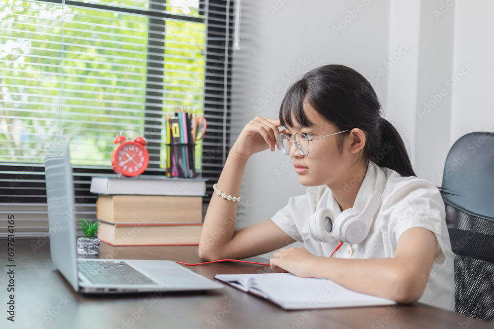 Smiling teen girl school student with glasses and black hair write notes watch video online webinar learn on laptop at home. Smiling teen girl school student with glasses and black hair write notes watch video online webinar learn on laptop at home.