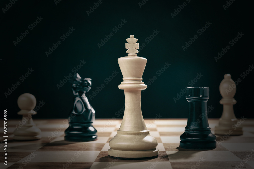 Different game pieces on chessboard against dark background Different game pieces on chessboard against dark background