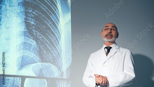 Middle aged Caucasian doctor presenting medical research using a projector screen.
