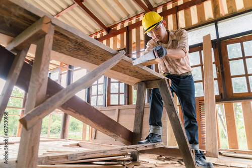 Asian carpenter cutting wood with hand saw on construction site build a house in the countryside