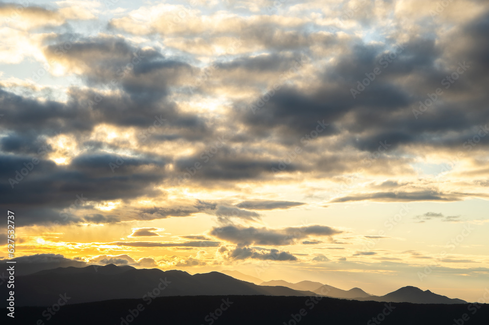 山のシルエットの上の朝焼けの空と雲。