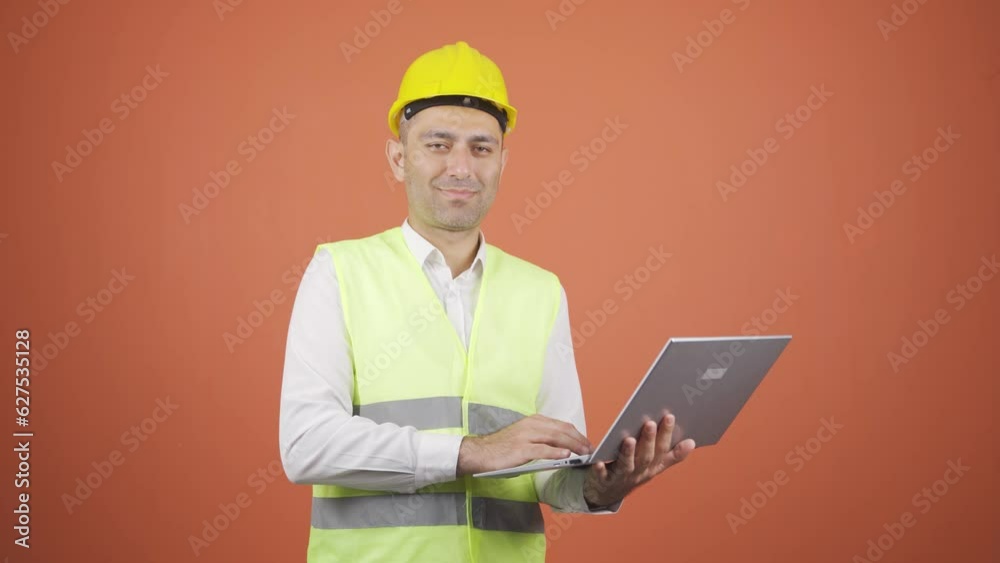 Engineer holding laptop laughing at camera. Engineer holding laptop laughing at camera.