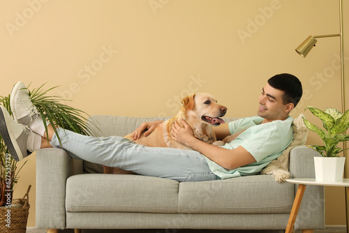 Young man with his Labrador dog lying on sofa at home