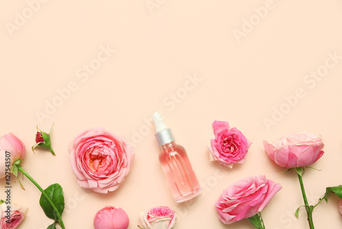 Fototapeta Naklejka Na Ścianę i Meble -  Bottle of cosmetic oil with rose extract and flowers on beige background