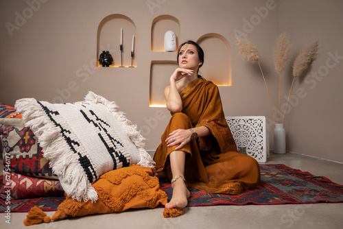 beautiful young woman sitting on the floor on a carpet in a traditional indian dress, selective focus