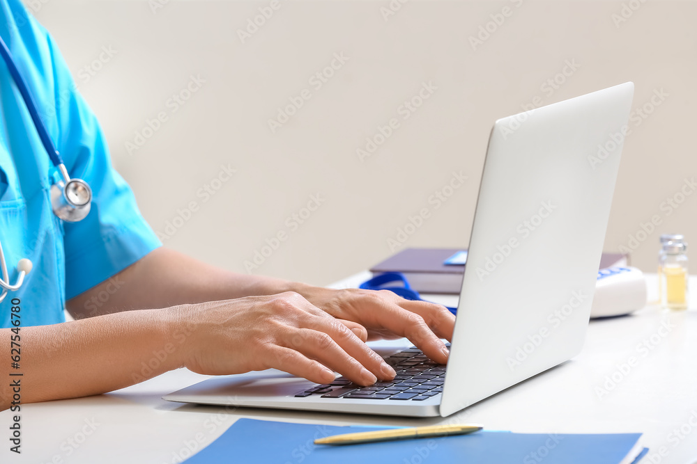 Fototapeta premium Female doctor working with laptop in clinic, closeup