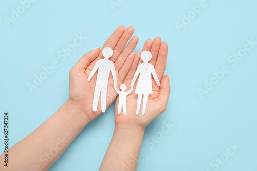 Woman holding human figures on blue background. Family love concept