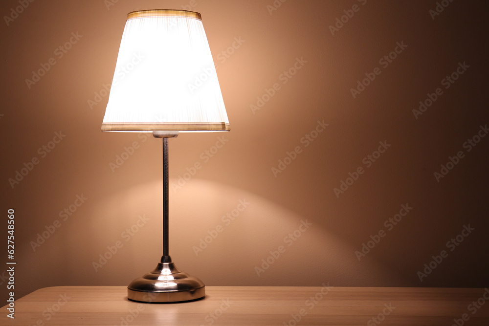 Glowing lamp on wooden table in dark room Glowing lamp on wooden table in dark room