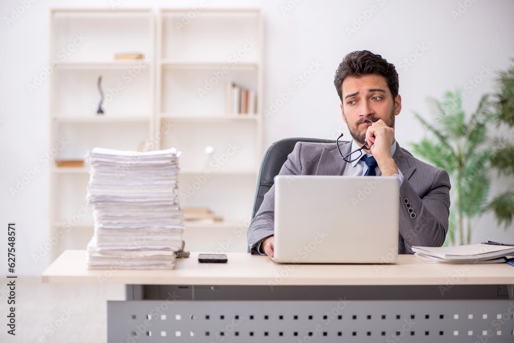 Young male employee and too much work in the office Young male employee and too much work in the office