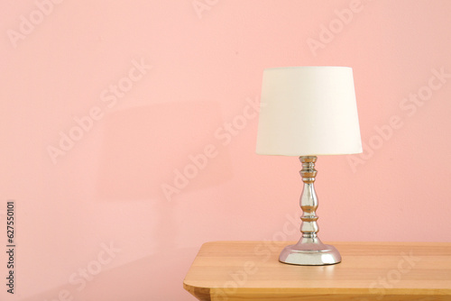 Lamp on wooden table near pink wall