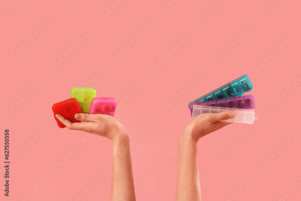 Female hands with different pill boxes on pink background Female hands with different pill boxes on pink background