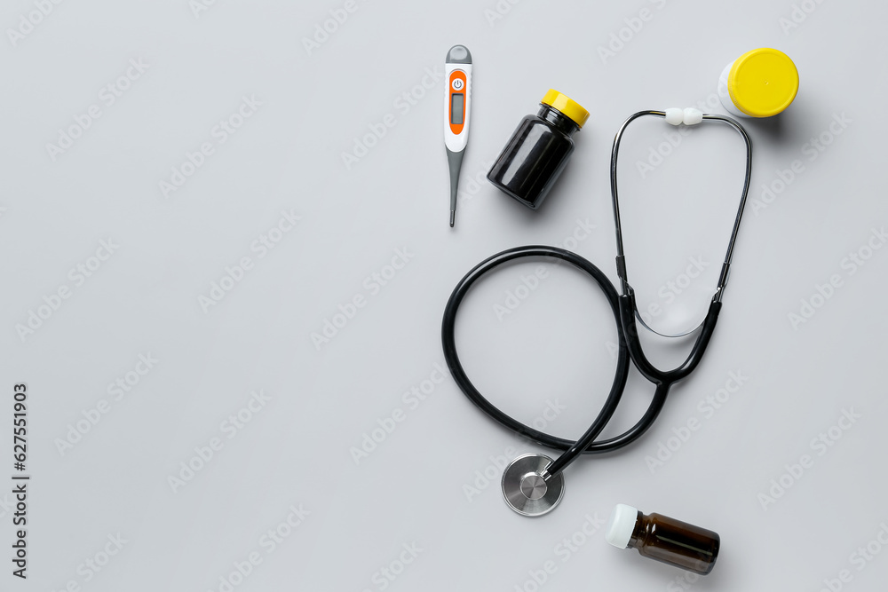 Stethoscope, pills and digital thermometer on grey background Stethoscope, pills and digital thermometer on grey background