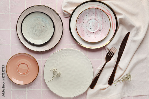 Composition with clean plates and cutlery on pink tiled table