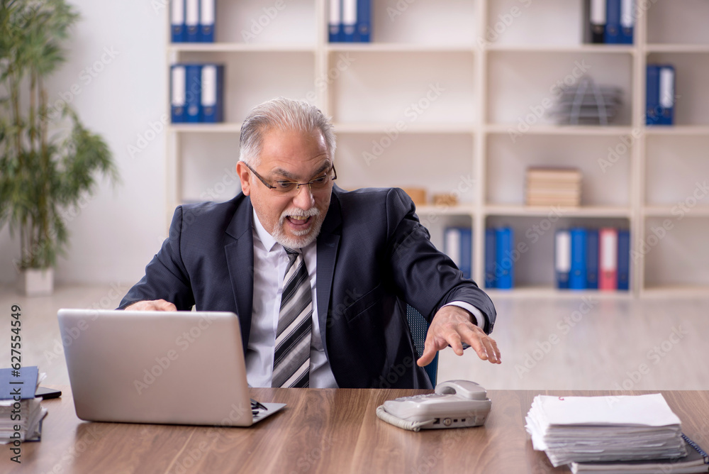 Old male employee working in the office Old male employee working in the office