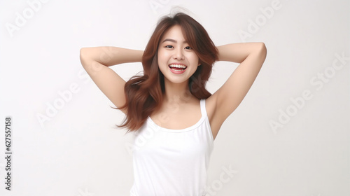 A young and pretty woman in a white underwear dress exudes joy and relaxation, raising her arms wide with a cute smile, revealing her smooth armpits against a pristine white background. Generative AI.
