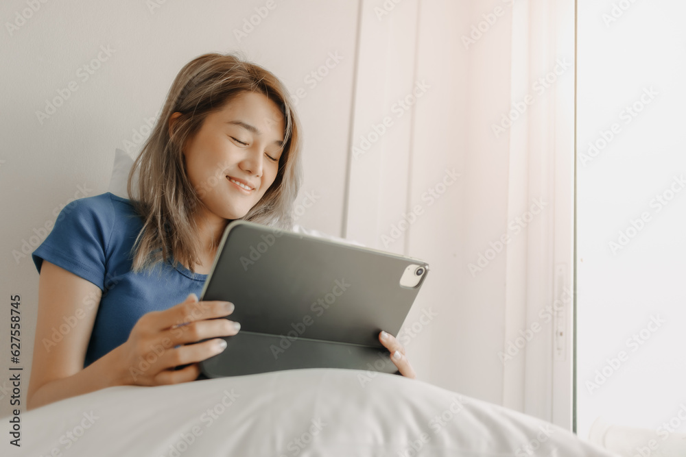Happy freelance asian woman work on tablet on the hotel bed on travel trip. Happy freelance asian woman work on tablet on the hotel bed on travel trip.