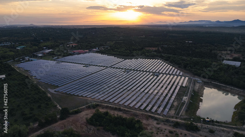 Aerial view of solar panels on sunset sky background, green clean Alternative power energy concept. Sunset rays over a photovoltaic power plant.