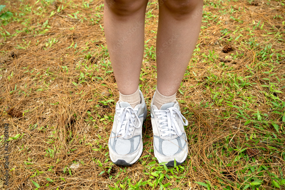 Women's legs with white shoes trekking in the forest