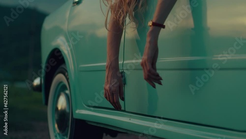 female hands dangle from the door of a retro car
