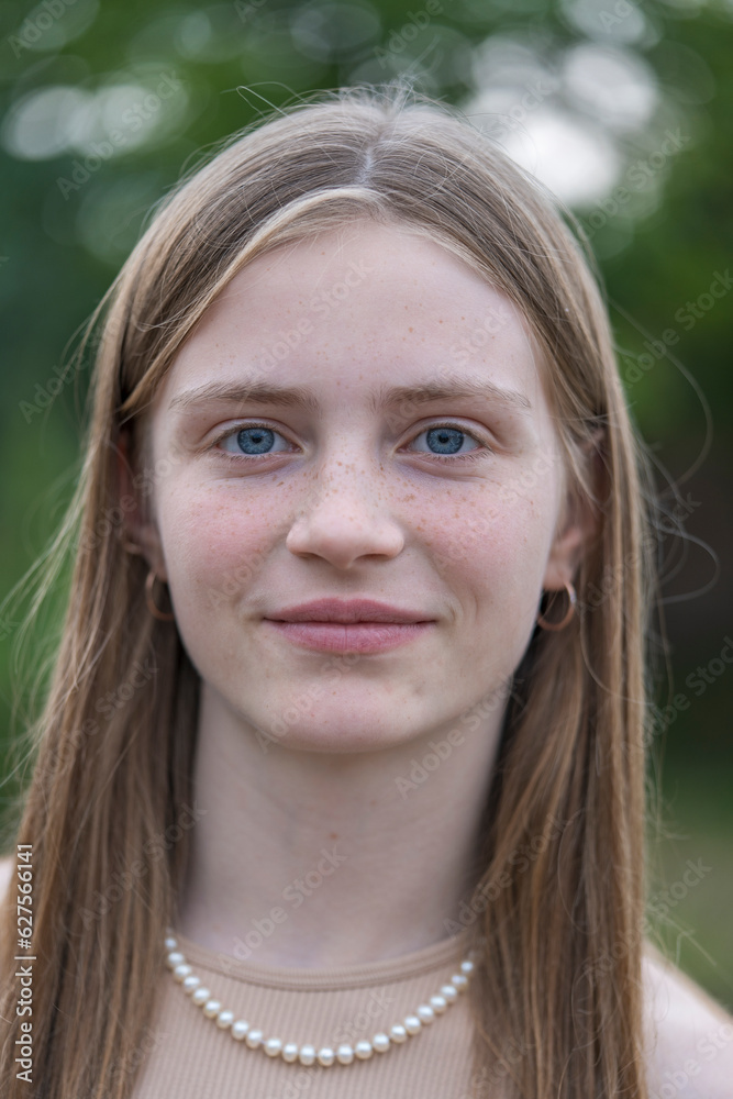 Portrait of a beautiful happy girl with blond hair and freckles looking at the camera and smiling charmingly, closeup, outdoors Portrait of a beautiful happy girl with blond hair and freckles looking at the camera and smiling charmingly, closeup, outdoors