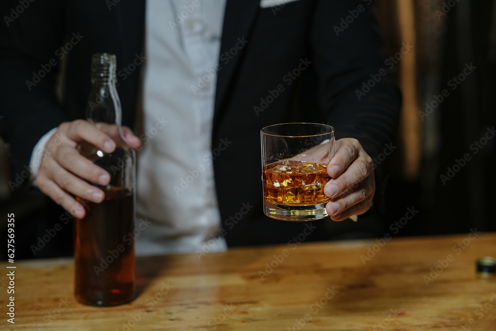 Businessman sitting and holding glass of whiskey..