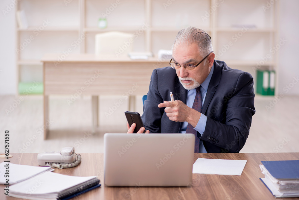 Old male employee working in the office Old male employee working in the office