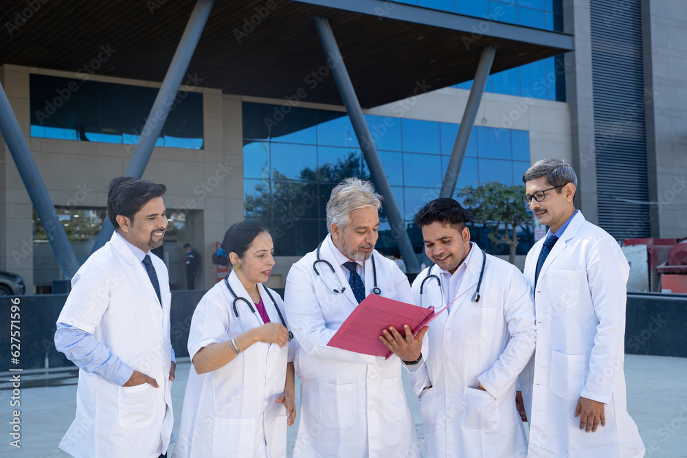 Senior doctor looking medical report and discussing to junior doctor team Senior doctor looking medical report and discussing to junior doctor team