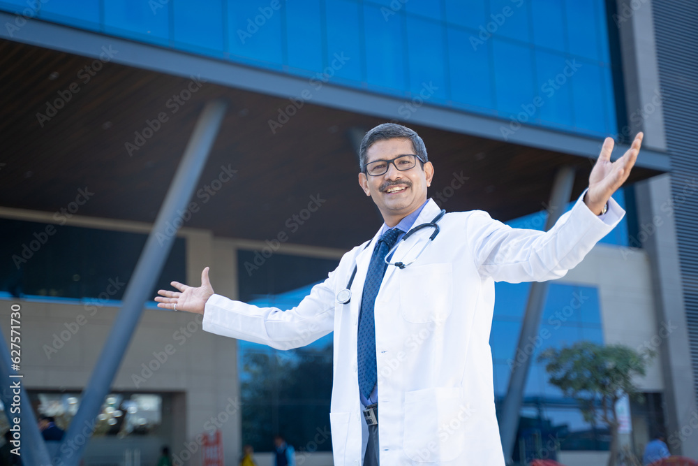 Confident Indian doctor spreading hand and giving happy expression out of hospital. Confident Indian doctor spreading hand and giving happy expression out of hospital.