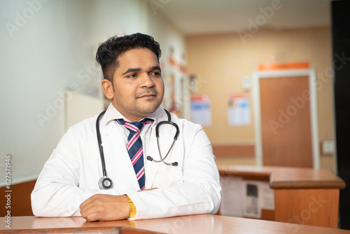Young indian doctor standing at hospital.