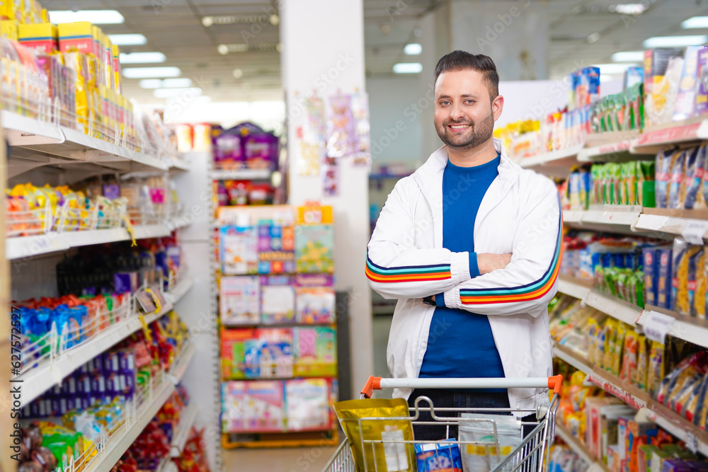 Obraz premium Young indian man standing at grocery shop.