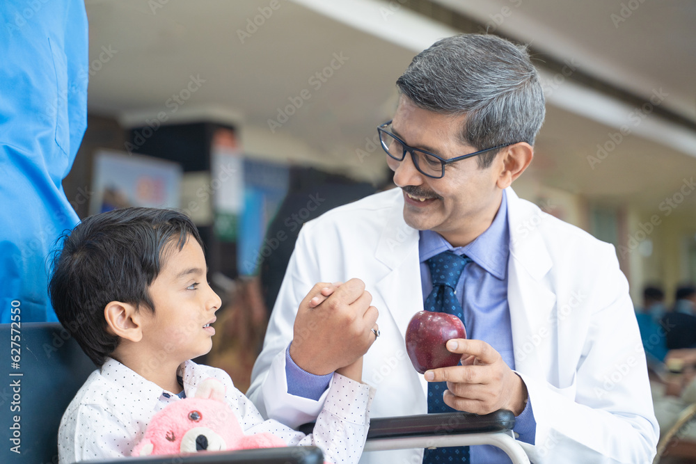 Doctor asking for eating apple to little boy patient