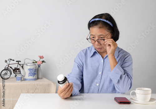 Senior woman sitting and reading drug labels