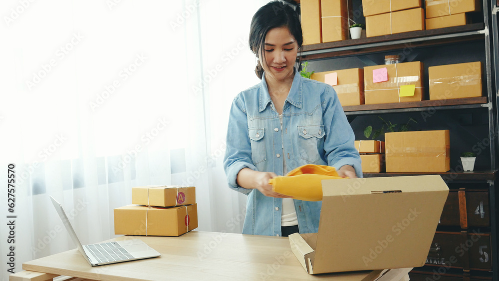 Fashion designer Women packing box on table checking goods quality package. Asian women startup small business at home office desk pack fashion design clothing. Asian woman packing startup business